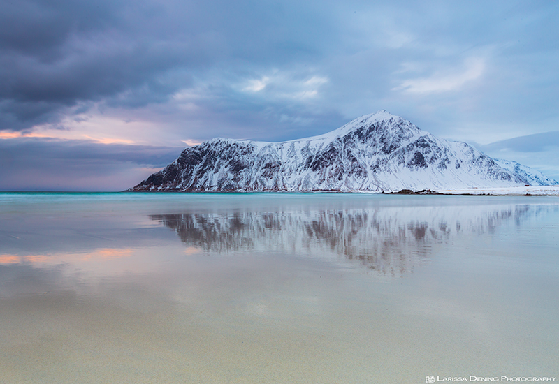Amazing reflections of snow capped mountains on the beach at Skagsanden, Lofoten, Norway